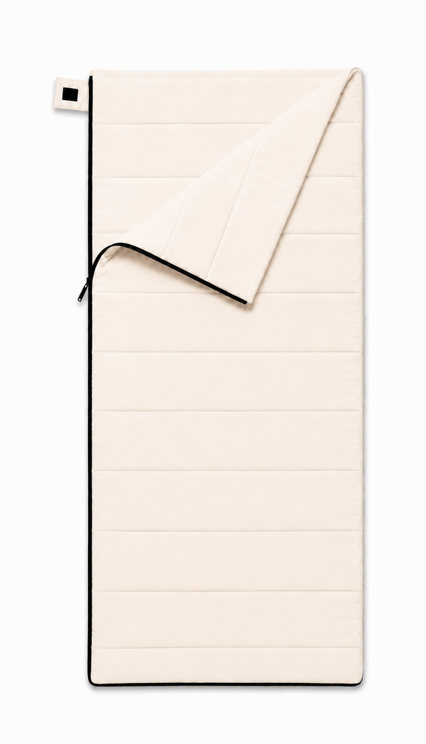 Adult organic cotton sleeping bag in undyed natural cotton, partly unzipped with the top corner folded back