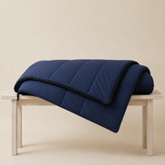 Navy blue organic cotton sleeping bag folded over a wooden bench