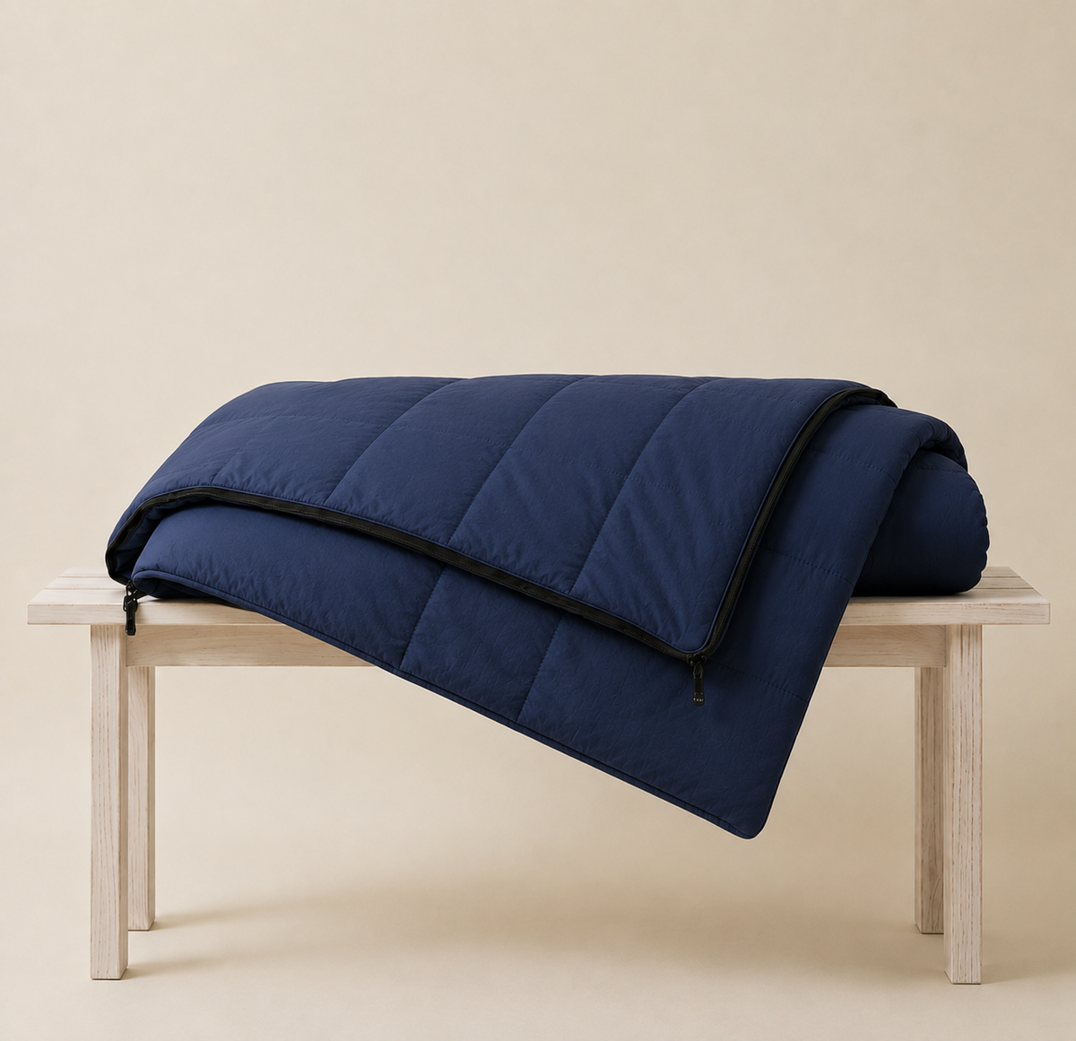 Navy blue organic cotton sleeping bag folded over a wooden bench