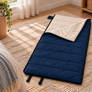 Navy blue junior organic cotton sleeping bag laid out on a rug beside a bed in a child's bedroom
