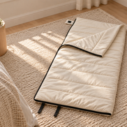 Undyed junior organic cotton sleeping bag laid out on a rug beside a bed in a child's bedroom