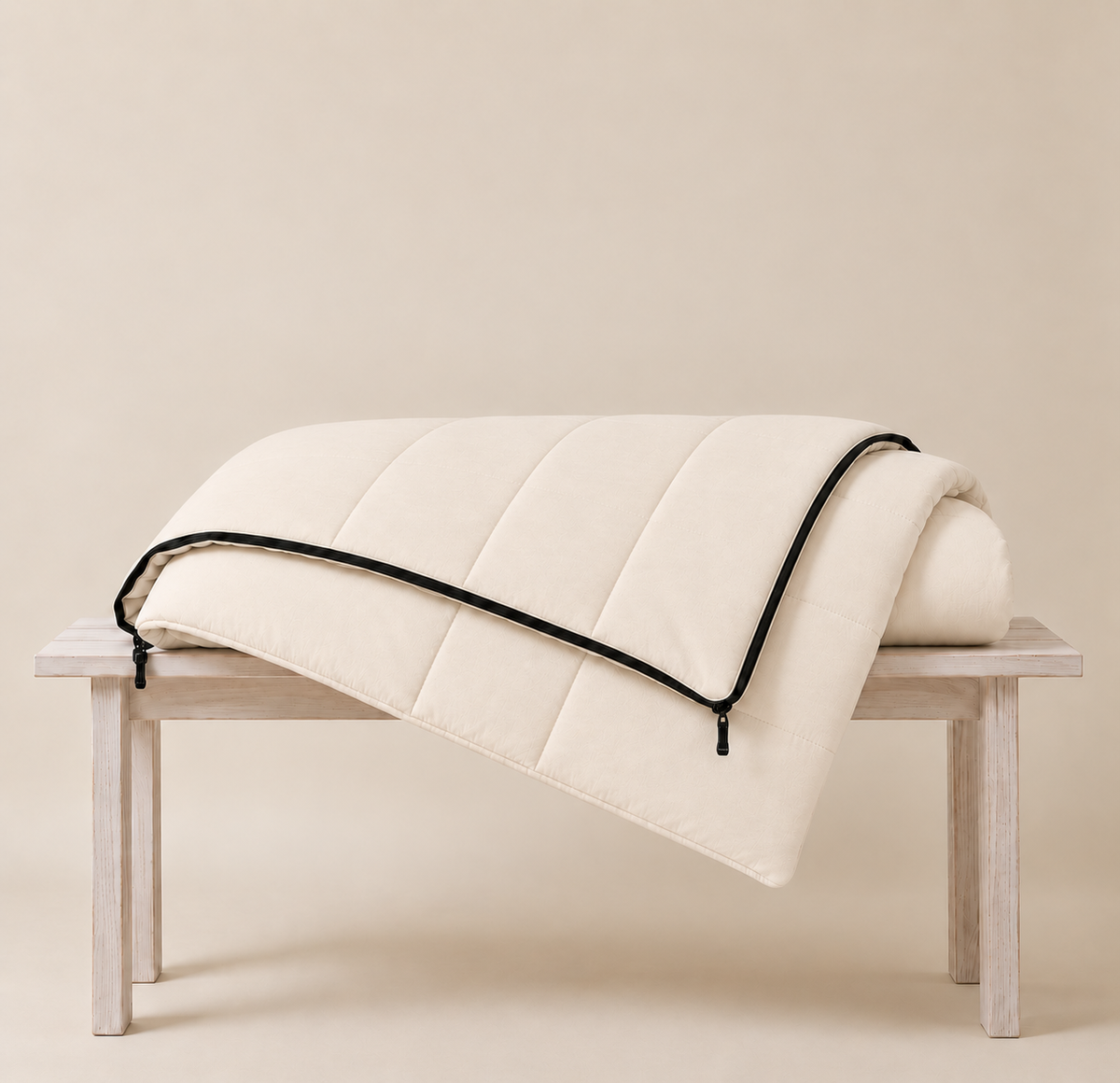 Undyed organic cotton sleeping bag folded over a wooden bench, showing its soft quilted channels