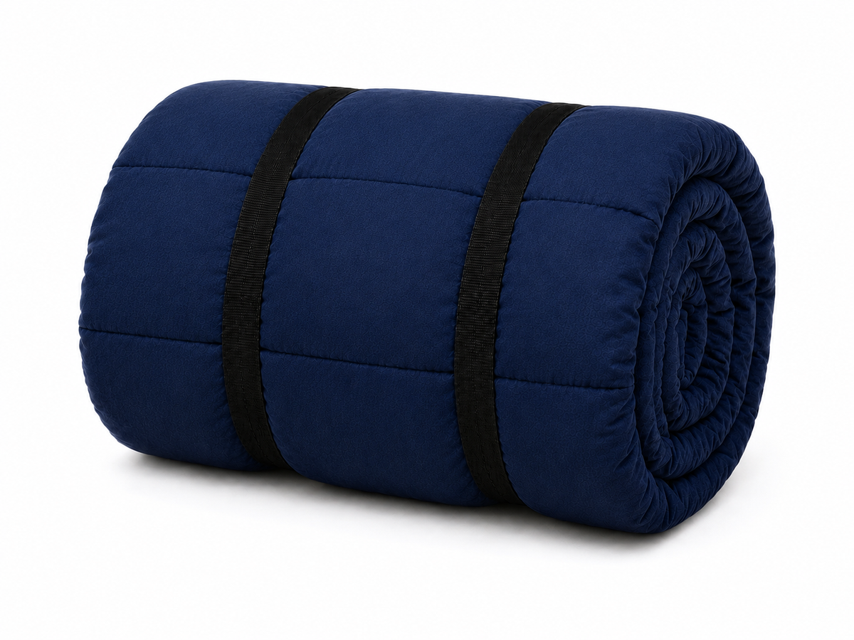 Navy blue organic cotton sleeping bag rolled up and secured with two black straps