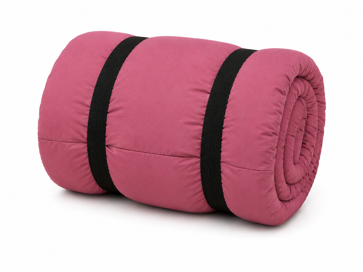 Pink junior organic cotton sleeping bag rolled up with two black straps