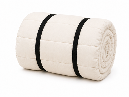 Undyed organic cotton sleeping bag rolled up and secured with two black straps